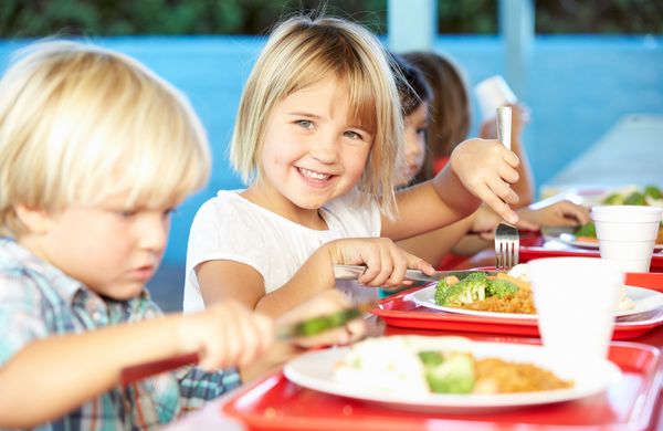 Elementary Pupils Enjoying Healthy Lunch In Cafeteria
